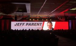 Jeff Parent speaks onstage at a Gulf States Toyota event, with his name and title displayed on a large LED screen in a dimly lit ballroom.