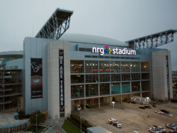 Exterior view of NRG Stadium at dusk with the "WE ARE TEXANS" slogan displayed prominently.