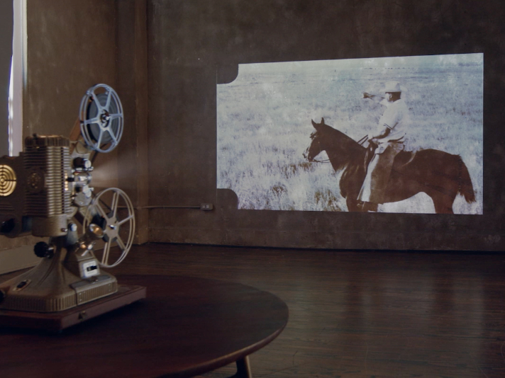 Vintage projector projecting image of cowboy on horse on a wall